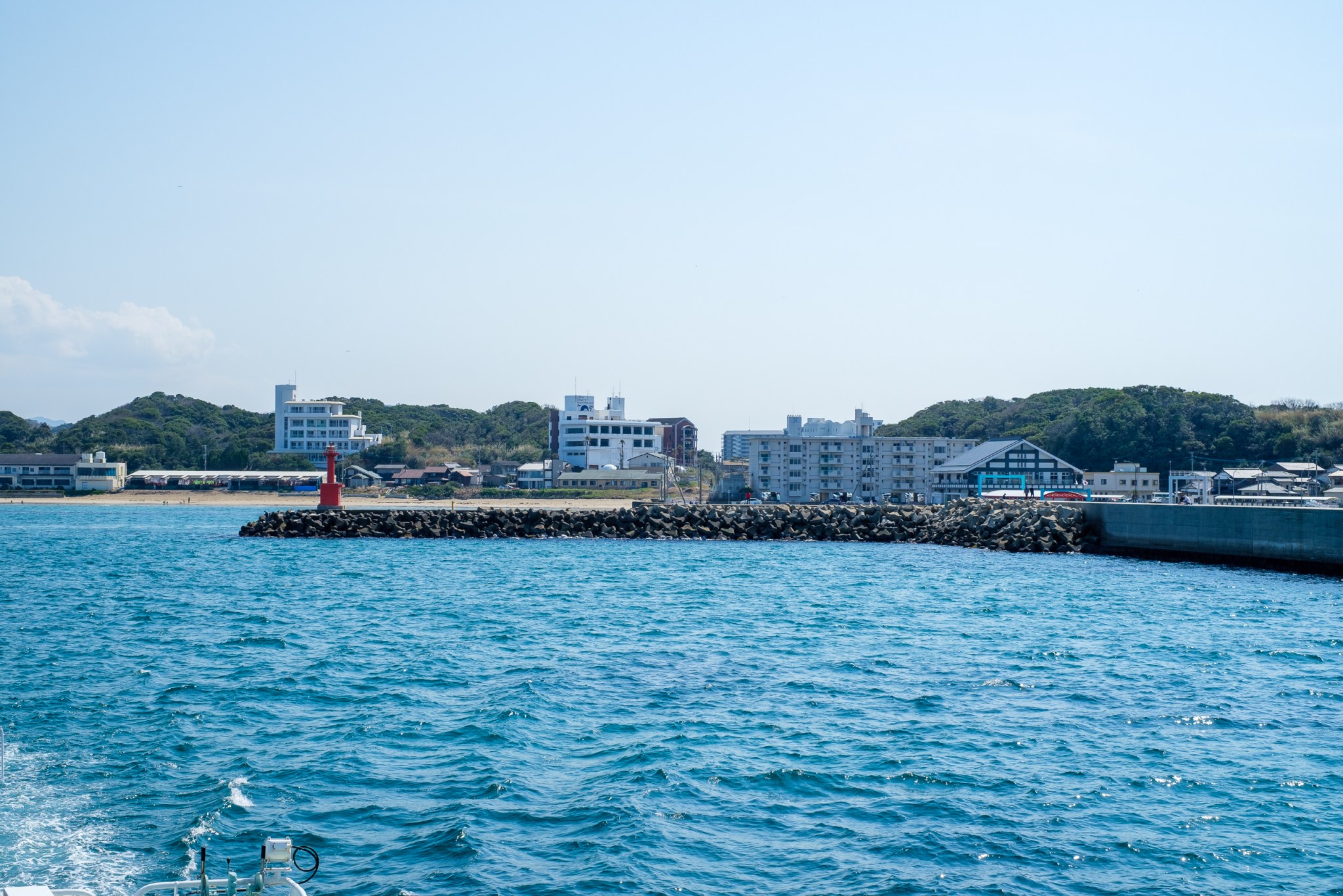 海港风景，蓝色海水和岸边建筑，红色灯塔在岩石堤防旁