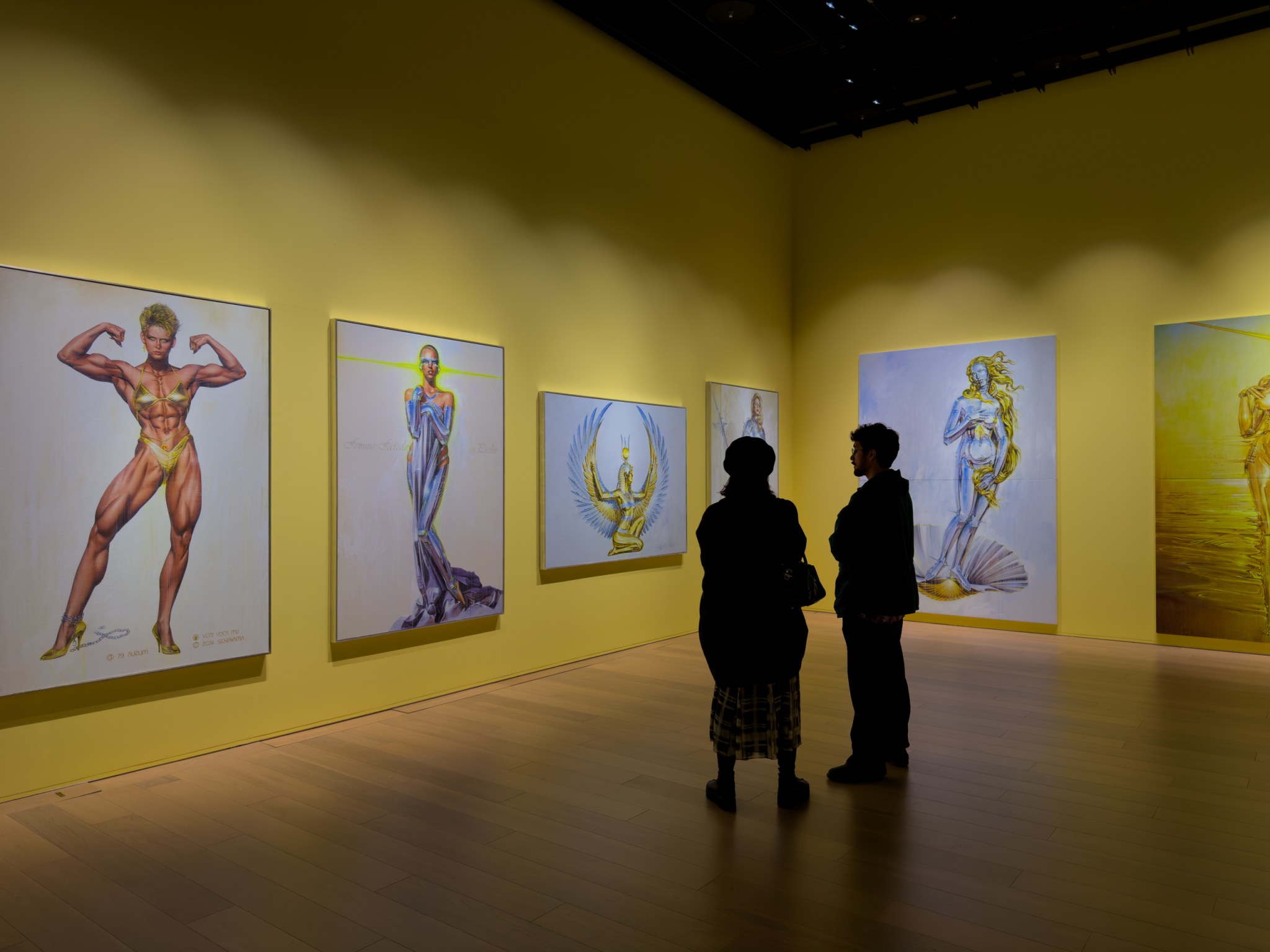 一个现代艺术展览厅,黄色墙壁上挂满了多幅绘画作品,观众正在欣赏艺术品。