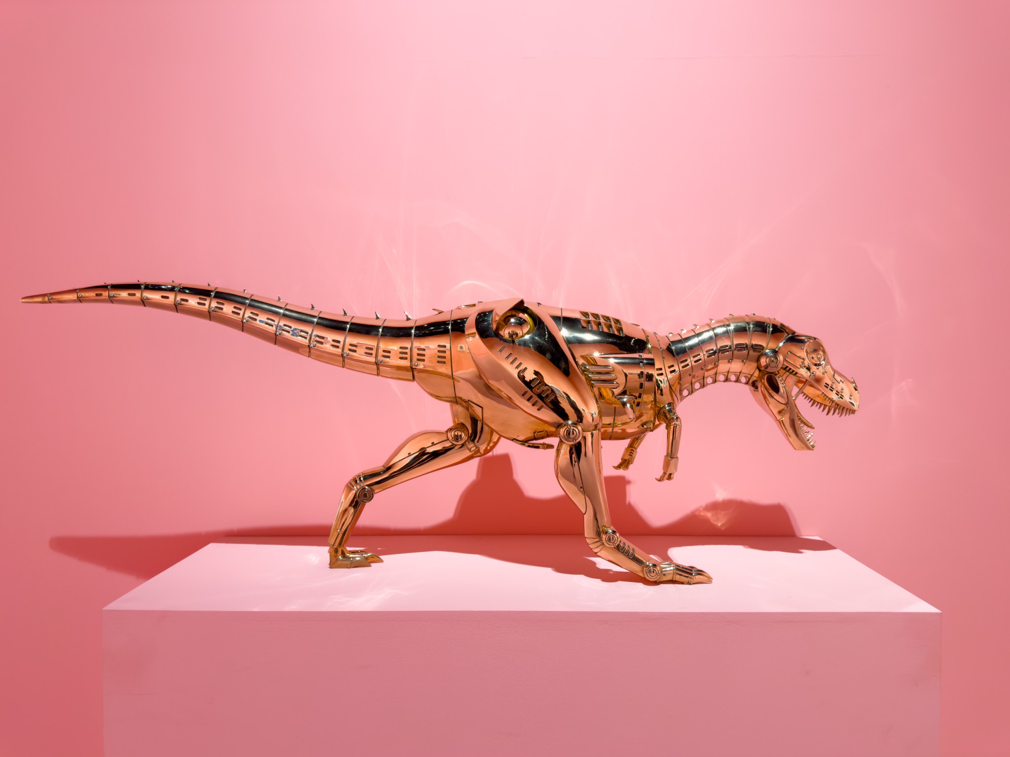 一只金属机械恐龙在粉色背景下展示。